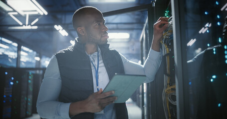 Data center technician inspects server racks, checks network cables.