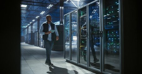 Data center sys admin inspects server racks, checks network cables usi