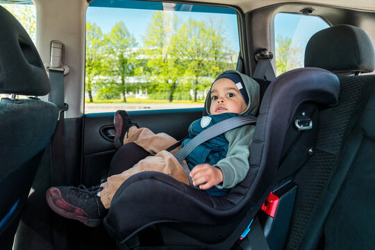 Child sitting securely in car seat by window