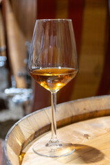 Visit of wine cellar with old large oak barrels, glass of fortified dry or sweet tasty marsala wine from barrels in Marsala, Sicily, Italy