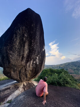 Anonymous traveler looks up on a massive boulder