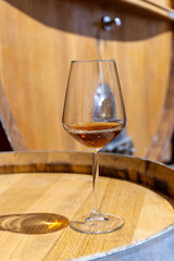 Visit of wine cellar with old large oak barrels, glass of fortified dry or sweet tasty marsala wine from barrels in Marsala, Sicily, Italy