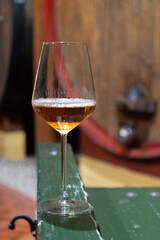 Visit of wine cellar with old large oak barrels, glass of fortified dry or sweet tasty marsala wine from barrels in Marsala, Sicily, Italy