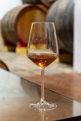 Visit of wine cellar with old large oak barrels, glass of fortified dry or sweet tasty marsala wine from barrels in Marsala, Sicily, Italy