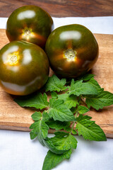 Fresh ripe sweet reddish brown and green kumato tomatoes on board
