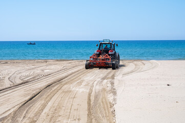 Beach maintenance work before the season, tractor cleans seaweed and loosens sand, paid beaches in...