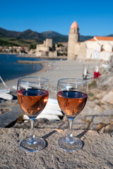 Glasses of rose Collioure AOC wine in sunlights with view on old town Collioure, colorful houses, church, castle and beaches, Occitanie, France, tourists destination