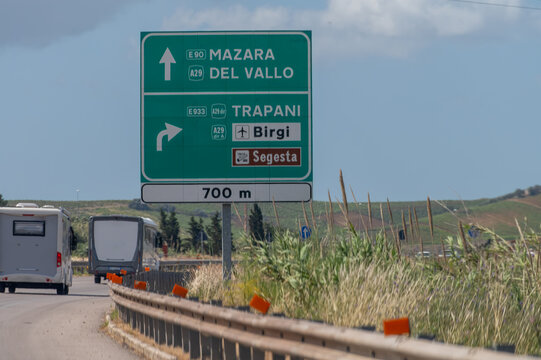 Fototapeta Road transportation on Sicily, Italy, green signs guide to cities by highways, blue signs by city roads. Arrows, distances, and exits help travelers navigate Sicily