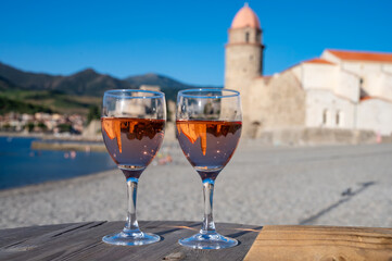Glasses of rose Collioure AOC wine in sunlights with view on old town Collioure, colorful houses, church, castle and beaches, Occitanie, France, tourists destination