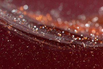 Close-Up of Bubbles and Sparkles in a Dark Red Liquid

