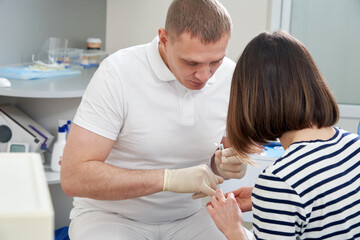 Fototapeta premium Male dentist showing his female patient a dental implant