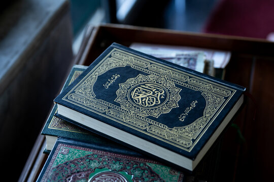 A stack of Quran books, the Islamic holy book, on a wooden table