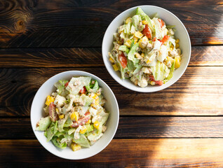 Fresh vegetable salad served in bowls on a wooden table. A healthy homemade dish full of vitamins.