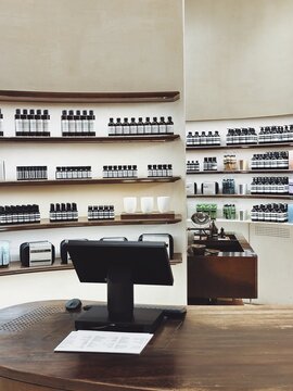 29.05.2025, Kuala Lumpur, Malaysia. Wooden store counter with computer checkout in front of shelves filled with skincare products  Aesop. Modern minimalistic retail interior.