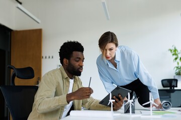 Black male architect showing something on tablet about windmill farm