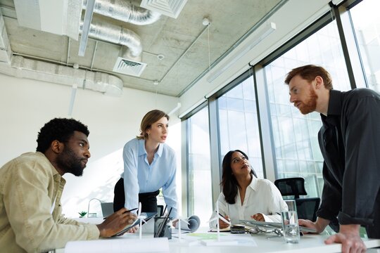 Bottom of multiracial architects listening red hair male colleague