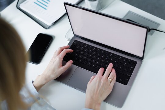 Top cropped view of businesswoman using laptop computer at desk