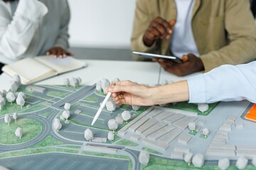 Partial architects pointing on area model during meeting at desk