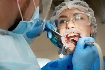 dentist drilling tooth to male patient in dental chair