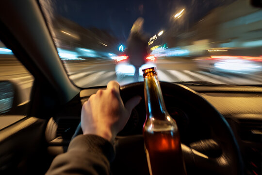 Anti-drunk driving ad: intoxicated driver's distorted view of road with alcohol bottle visible.
