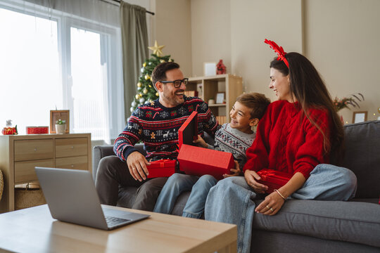 Happy family opening christmas gifts during video call