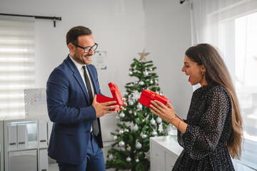 Businessman and businesswoman exchanging christmas gifts in office