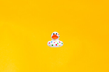 Colorful rubber duck floating in vivid yellow background creates a cheerful and playful atmosphere