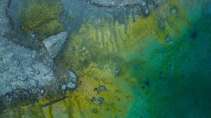 Aerial view of colorful shoreline with green and turquoise water meeting rocky coast unique natural texture and abstract landscape photography