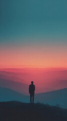 Obraz premium A lone figure stands overlooking a breathtaking mountain landscape at sunrise.