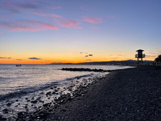 Fototapeta premium Breathtaking Sunset at the Beach in Andalucia, Spain - Colorful Sky, Tranquil Sea, and Lifeguard Tower on Empty Shore