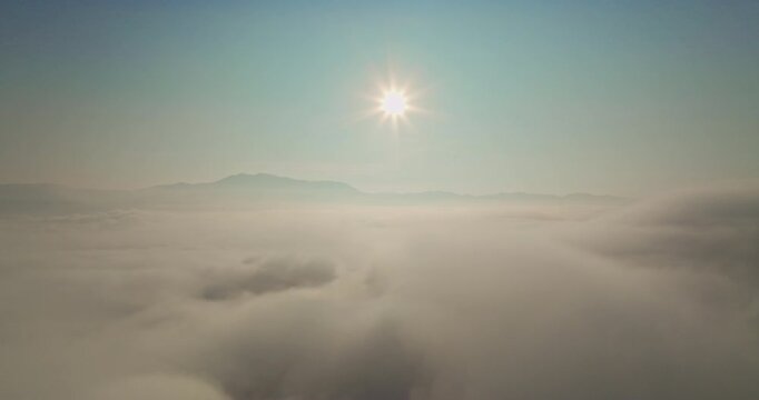 Aerial view Golden Sun Shining Over Cloud Valleys. An inspiring panorama of the bright sun illuminating a cloud sea, where mountains meet the horizon in a tranquil and uplifting natural atmosphere.