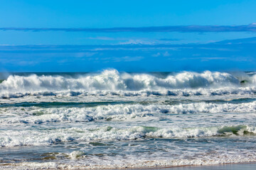 Photograph of waves from the Tasman Sea crashing onto Jones Beach against a blue sky near the town of Kiama Downs in the Illawarra region on the south coast of NSW, Australia.