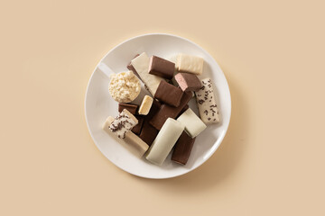 Whey protein bars with various coatings in white plate on beige background. Healthy fitness snacks. View from above