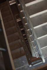 Looking down a tall concrete stairwell with metal railings, creating a dramatic perspective and geometric pattern in vertical view.