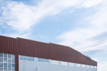 Contemporary industrial facility exterior featuring a red and white metal panel facade with silver exhaust or ventilation pipes. Concept modern industrial architecture.
