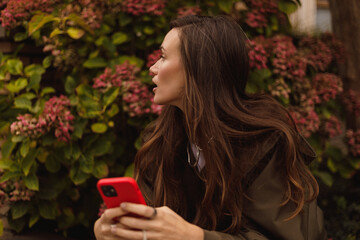 Attractive brunette woman wear raincoat hold mobile phone and look at side, look calm. Amazing...