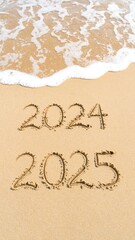 New year 2024, 2025 written in the sand on a beach.  Ocean waves lapping at the shore