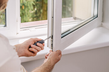 A repairman is installing a PVC window frame in a residential apartment