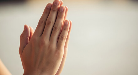 Close-up of clasped hands, fingers interlocked, showcasing a gesture of prayer or meditation, symbolizing faith, hope, and serenity