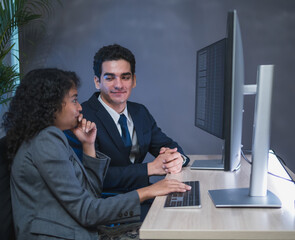 Man and woman team business professional formal attire collaborate desk with dual monitor computer talk about financial stock market in modern office highlight teamwork technology, professional work