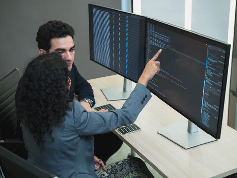 Man and woman team business professional formal attire collaborate desk with dual monitor computer talk about financial stock market in modern office highlight teamwork technology, professional work