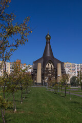 Fototapeta premium Orthodox church with scaffolding, golden dome and unfinished facade against blue sky, religious architecture in progress with copy space.