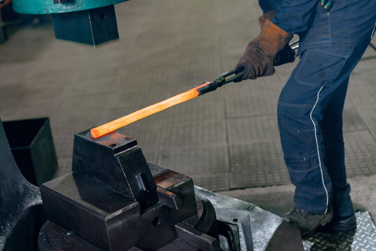 Blacksmith Worker uses hydraulic hammer to make repair part for an industrial machine