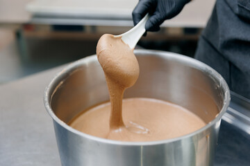 Baker confectioner prepares fresh urbech paste of nuts in kitchen of bakery