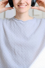 Happy girl listening to music online with wireless headphones from smartphone. Woman is having fun with music with a phone and headphones. Girl uses wireless earphones