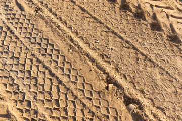 car tracks in the sand on a part of the road in a field, sand on the road in a field with traces of heavy agricultural or construction vehicles