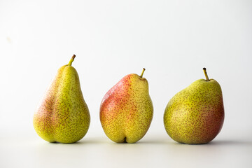 Three fresh Forelle pears standing in a line.