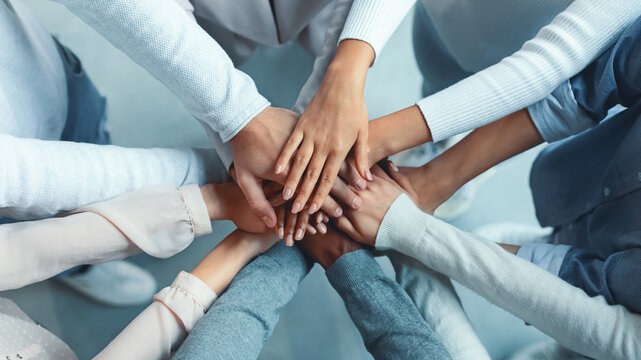 Top view of multiracial business team demonstrating cooperation with putting their hands together on top of each other