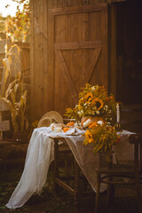 Beautiful fall seasonal wedding decor or thanksgiving family dinner arrangement outdoors. Countryside style, cottage core. Centrepiece floral composition with natural sunflowers in a pumpkin vase