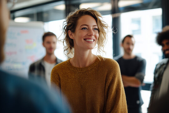 Young woman smiling confidently in casual sweater during a collaborative team meeting in a modern office space